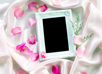 the Empty photo frame with a bouquet sweet pink roses  petal on  soft pink silk fabric , romance and love card concept