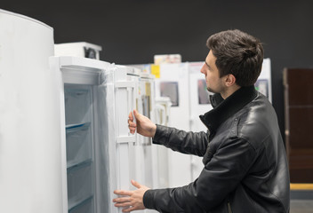 Fototapeta na wymiar portrait of male customer choosing refrigerator in supermarket store. He opened fridge cover