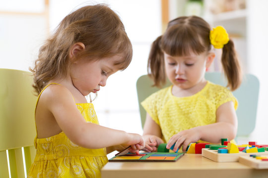 Kids playing with logical toy on desk in nursery room or kindergarten. Children arranging and sorting shapes, colors and sizes.