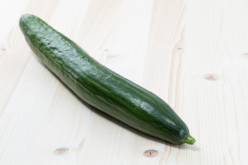 Green cucumber on a pine wood table board