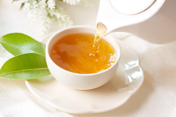 Gros plan versant du thé noir chaud dans une tasse de thé blanc, concept de temps de cérémonie du thé