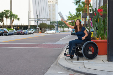 Handicapped woman in a wheelchair hailing a taxi waving newspaper