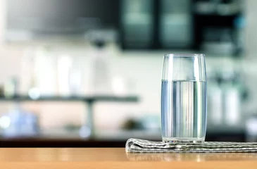 Tuinposter Glas gezuiverd water op de tafelbar in de keuken © Cozine