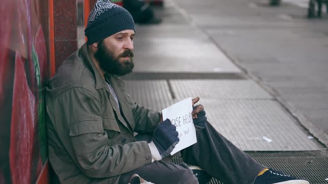 lonely sad homeless sitting on the street asking for alms