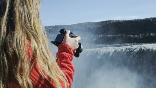 woman taking photograph of waterfall