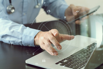 smart medical doctor working with smart phone and stethoscope and laptop and digital tablet computer on dark wooden desk with virtual icon diagram