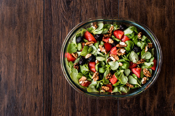 Purslane salad with walnut, tomatoes and olive on wooden surface.
