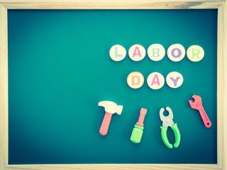 Labor day background concept - Happy labor day text with tools toy on greenboard background top view