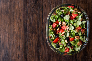 Purslane salad with walnut, tomatoes and olive on wooden surface.
