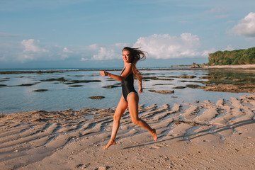 Beautiful stylish girl in a swimsuit on the rocky beach in Indonesia 