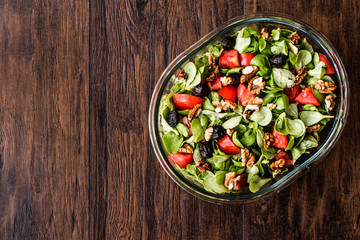 Purslane salad with walnut, tomatoes and olive on wooden surface.