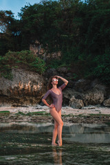 Beautiful stylish girl in a swimsuit on the rocky beach in Indonesia 