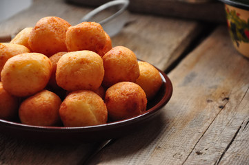 Small balls of freshly baked homemade cottage cheese doughnuts in a plate on a wooden background. Rustic style.