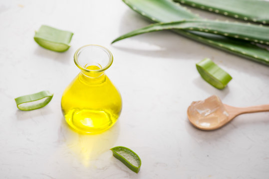 Aloe vera essential oil and aloe leaves on a white background.