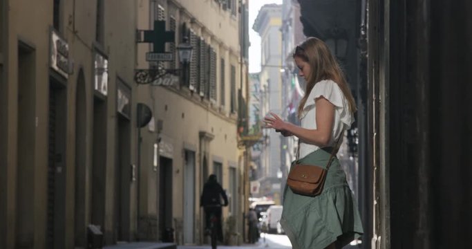 Girl in street in Italy on cell phone, pauses to look around