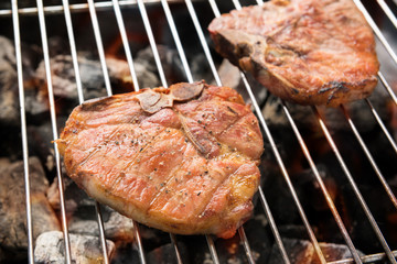 Grilled pork steaks over flames on the grill