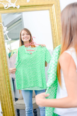 Lady holding top against body, looking in mirror