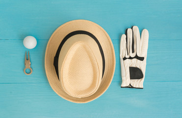 Golf concept : panama hat, glove, golf balls, divot repair tool on wooden table. Flat lay with copy space.