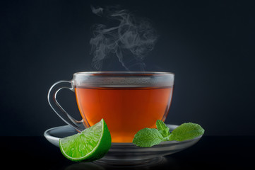 Cup tea with mint and lime on a black background
