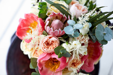 bridal bouquet with peonies and protea and boutonniere on the wooden floor