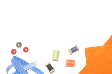 Coil with thread, scissors and ruler on a piece with a bright cloth, on a white background