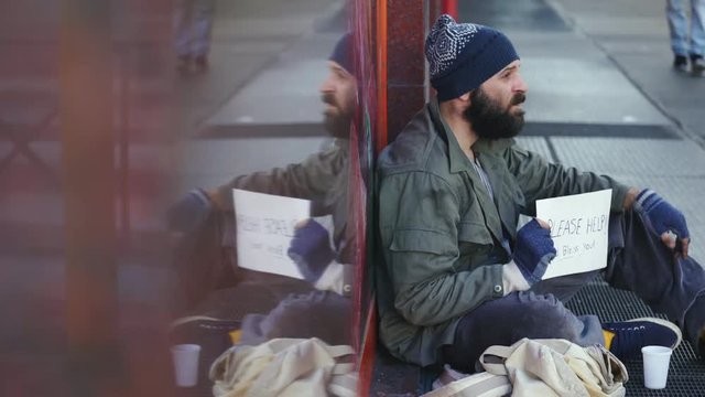 lonely homeless sit in the crowd sidewalk receives money from pedestrian