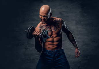 Obraz na płótnie Canvas Positive shaved head shirtless male dressed in a jeans holds the dumbbell.