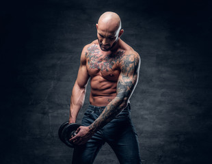 Positive shaved head shirtless male dressed in a jeans holds the dumbbell.