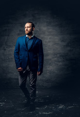 Fototapeta premium Full body studio portrait of stylish bearded male dressed in a suit and sunglasses.