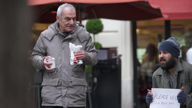 Sweet compassionate old man brings breakfast to a beggar in the street