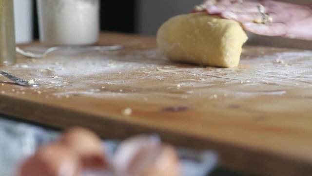 housewife's hands kneading the dough on wooden cutting board