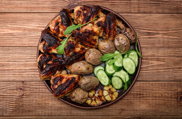 Chicken wings with baked potatoes on wooden background.