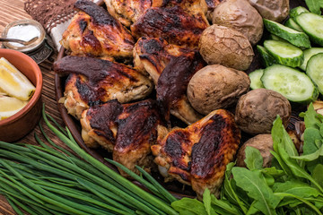 Chicken wings with baked potatoes on wooden background.