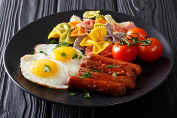 Farfalle pasta with fried eggs and sausages close-up. horizontal