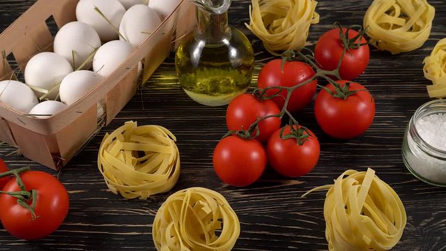 pasta, eggs, oil, tomatos and garlic on wooden background