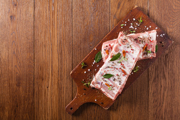 Raw pork ribs, on a plate sprinkled with spices.