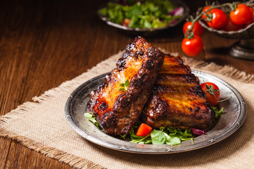 Roasted ribs, served on an old plate. Dark or black background.