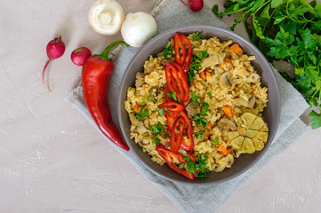 A traditional Asian dish - pilaf with meat, mushrooms and pepper capi in a bowl. The top view.