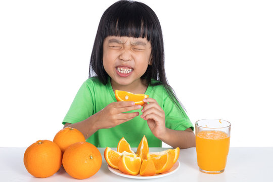 Asian Chinese Little Girl Eating Sour Orange And Making Grimace