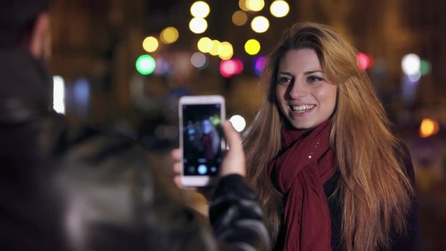 Boyfriend takes a picture to the cute girl in the city nights