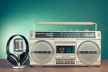 Retro radio cassette recorder, headphones and microphone on table in front mint green background....