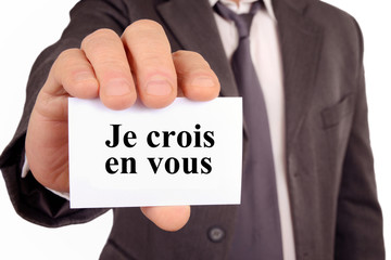 Homme tenant une carte avec je crois en vous écrit dessus 