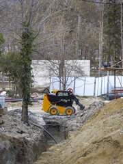 day view of mini yellow excavator with shovel in action at construction site