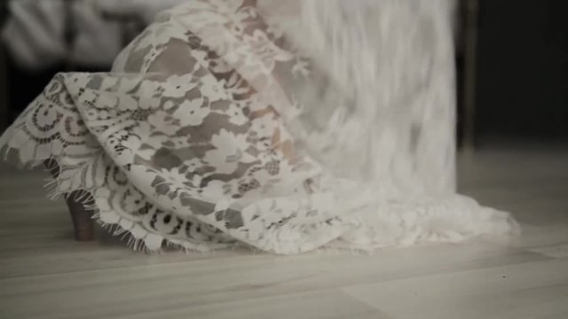 first wedding night. bride comes to a bed, removes shoes and lace dress. close-up young woman legs.
