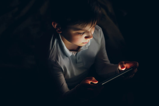 The Boy Is Holding A Tablet At Night