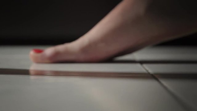 close up on Bare feet of woman with red nail varnish walking on the floor