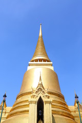 Golden pagoda against blue sky background on display at wat pra kaew in Bangkok, Thailand.