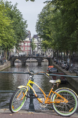 Fototapeta na wymiar Yellow and green bike near the canal and old bridge in Amsterdam