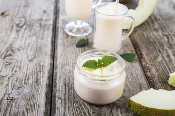 Obraz na płótnie Canvas Yogurt and smoothie with melon on a wooden table.