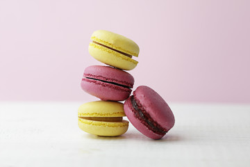 Pink and yellow macarons over an old white wooden table and pink background
